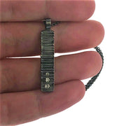 Close up image of Zen Galaxy Pendant 3 Stone Bar with hand in background to give idea of scale.