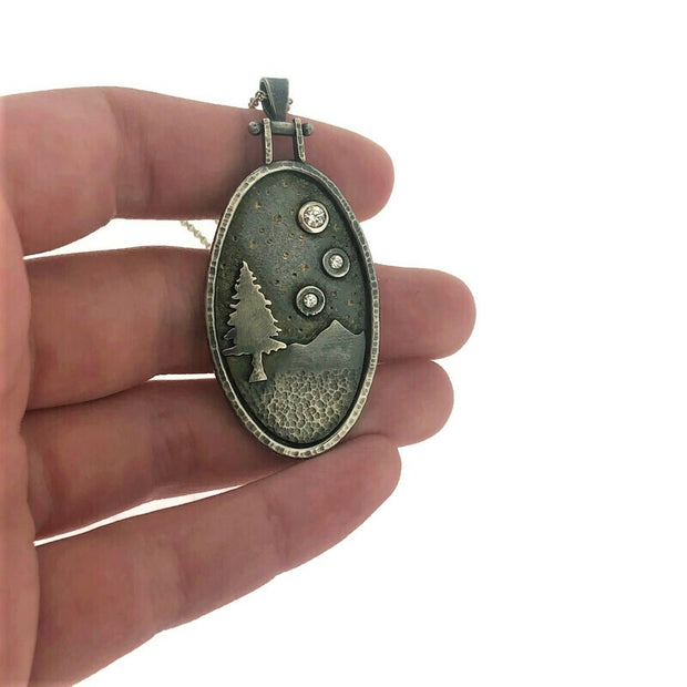 Close up image of pendant of Starry Night Pendant with CZ Ovals with Hinge with hand in background to give scale.