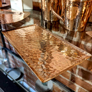 Full view of Copper 8" Tray on table next to copper mugs and other copper tray.