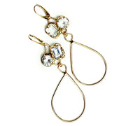 Gold earrings with organic prong set White topaz gemstones and long tear drop shaped dangles.