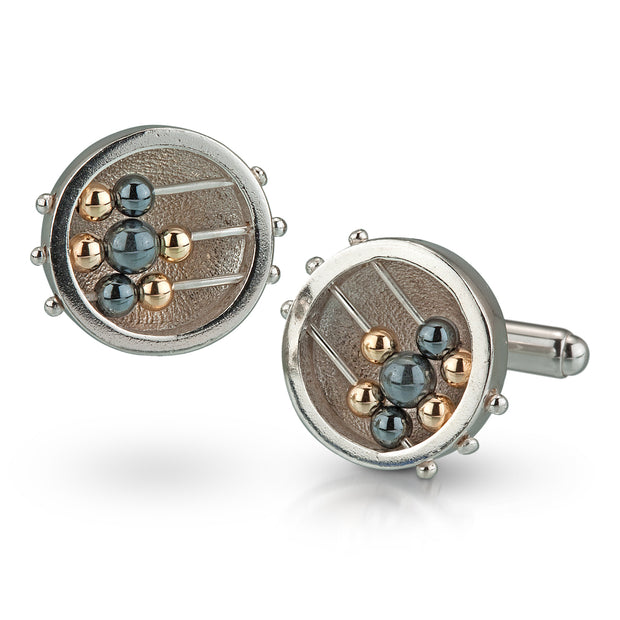 Full view of Round Abacus Cufflinks. These silver cufflinks are in the shape of a circle with three silver wire running through them. On the top and bottom wires are one gold bead and one hematite bead. The middle wire has two gold and one hematite bead in the middle, all of them are freely moving.