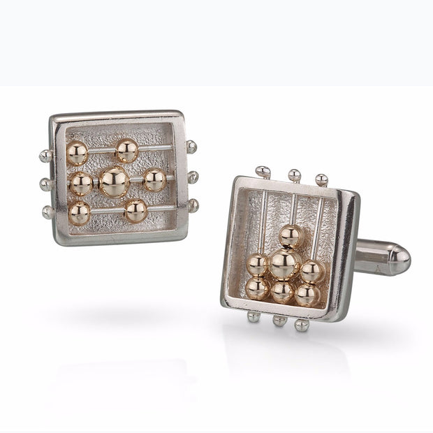 Full view of Square Abacus Cufflinks. these silver cufflinks are in the shape of a square with three silver wires running through them, the bottom and top wire holding two gold beads each and the middle wire holding three gold beads.