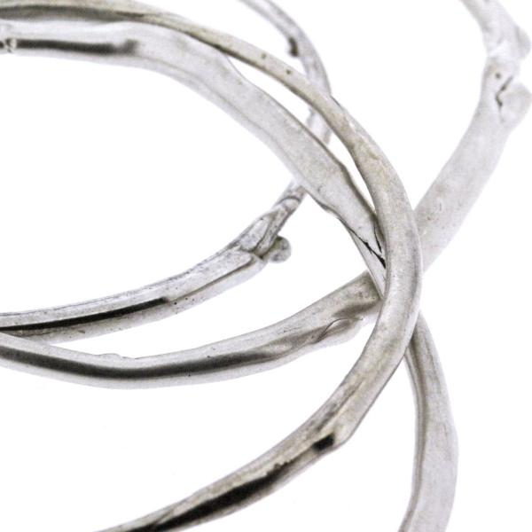A detail photo of a stack of sterling silver bangle bracelets that have a smooth organic texture that looks as if they are twigs covered in ice.