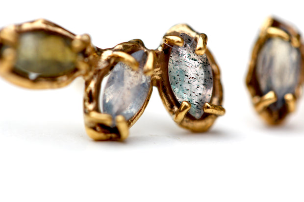 Detail photo of gold earrings with labradorite stones set with organic prongs.