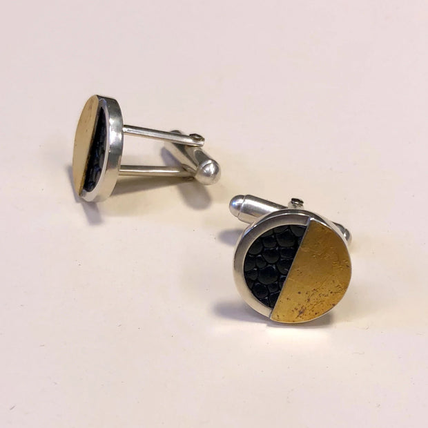 Full view of front and side profile of G.F. Cufflinks. these cufflinks are in the shape of a circle, outlined in silver, inlaid with black leather, and half covered in gold.