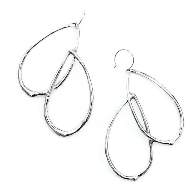 An statement earring featuring curved tear-drop shaped forms with an organic texture resembling a smooth twig or vine.