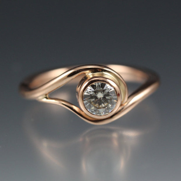 Rose Gold and Moissanite Engagement Ring, the metal gently wraps around the stone, like a vine or wave.