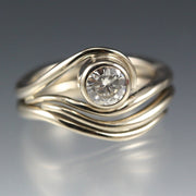 White Gold and Moissanite Engagement ring and nesting wedding band that have a vine or wave appearance.