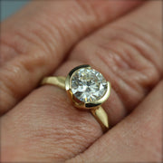 A contemporary partial bezel engagement ring on a woman's hand.