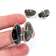 Full view of Cassius Studs with hand in background to help give an idea of its scale. Irregularly shaped and smoothly tumbled Labrodorite stones are set simply in Sterling Silver. 