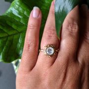 Full view of Botania Ring on woman's hand to help give an idea of its scale. This gold ring has a set circle moonstone which is surrounded by Katie's signature seasponge.