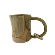 Full image of Ring mug made with a variety of creams, tans, and whites. There is a circle ring that dangles from the handle of the mug.