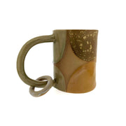 Full image of Ring mug made with a variety of creams, tans, and whites. There is a circle ring that dangles from the handle of the mug.