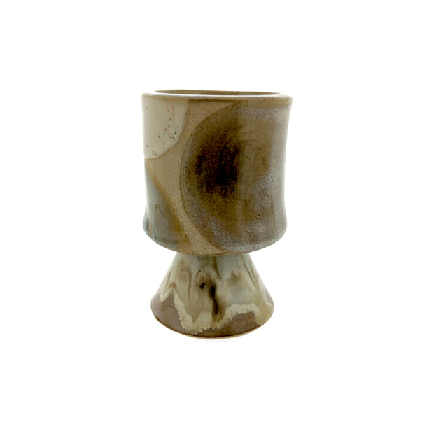 Full image of liquor sipper with cone pedestal. Made with a variety of creams, tans, and whites. 