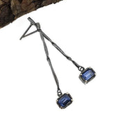 Full view of Blue Sapphire Gina Dangle Earrings. A contemporary, organic twist on a simple stick earring featuring a dangling emerald cut Blue Sapphire.