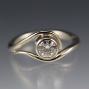 White Gold and Moissanite Engagement Ring, the metal gently wraps around the stone, like a vine or wave.