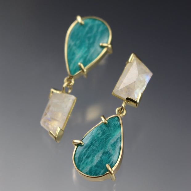 Full image of Amazonite and Moonstone Asymmetrical Earrings. These earrings have the amazonite in the shape of a teardrop and the moonstone in an asymmetrical rectangle all encompassed in gold. These earrings are asymmetrical in that the moonstone and amazonite are flipped in the corresponding earring.