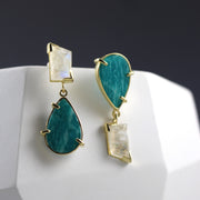 Full image of Amazonite and Moonstone Asymmetrical Earrings. These earrings have the amazonite in the shape of a teardrop and the moonstone in an asymmetrical rectangle all encompassed in gold. These earrings are asymmetrical in that the moonstone and amazonite are flipped in the corresponding earring.