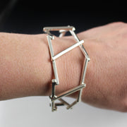 A woman's wrist wearing a dramatic, architectural sterling silver cuff bracelet.