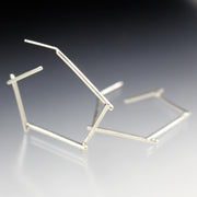 Full view of silver small stick hoop earrings, one propped up and on laying down.