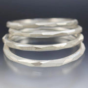 A stack of sterling silver bangle bracelets that have a faceted texture.