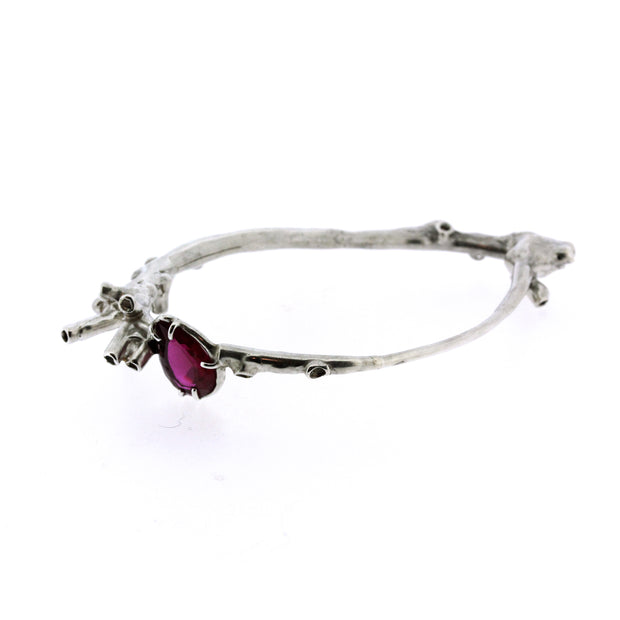 Full view of camari Bangle. Organic, sculptural tube like features wrap the wrist in an irregular shaped bangle.  A Lab Grown Ruby is perched amongst clusters of sea-sponge like details.  