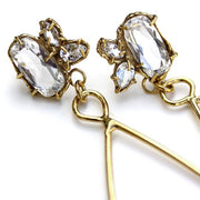 Detail photo of the top section of a pair of gold earrings a cluster of three white topaz gemstone set in an organic prong setting.