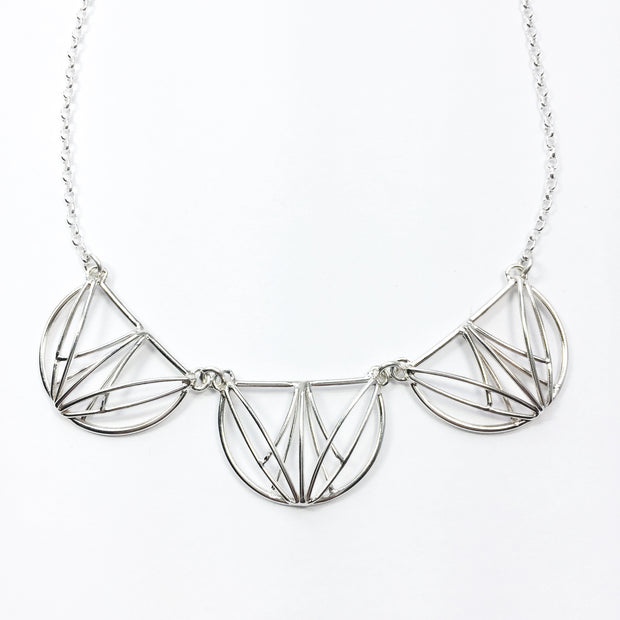 Close up image of pendants on Tripple Openwork Collar Necklace. these three pendants resemble the shape of half circles that are created in architectural lines with silver wire.