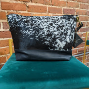 Full image of Virginia shoulder bag in a black and white cowhide print. Has black leather accents on bottom of bag and straps.