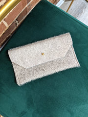 Full image of grey phone clutch laying down on chair.