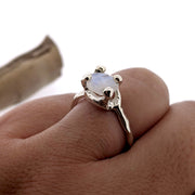 organic design rainbow moonstone and sterling silver solitaire ring, shown on a finger.