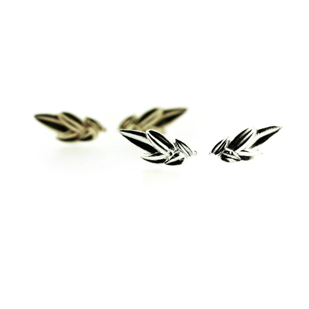 Full view of silver and gold Alyvia Crawler Earrings , one behind the other. These earrings are in the shapes of leaves and designed to travel up your earlobe when worn.
