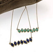 Full view of two Cherin Necklaces one in emerald and the other blue.