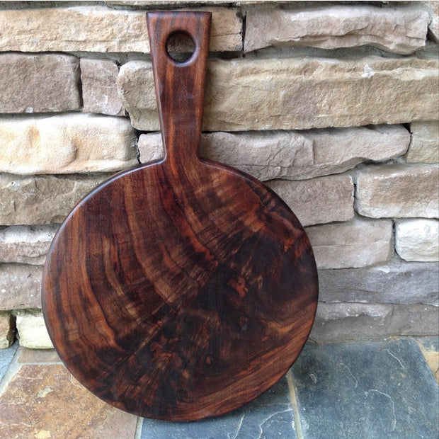 Full view of 12" Round Walnut Cutting Board. In the shape of a circle with a handle.