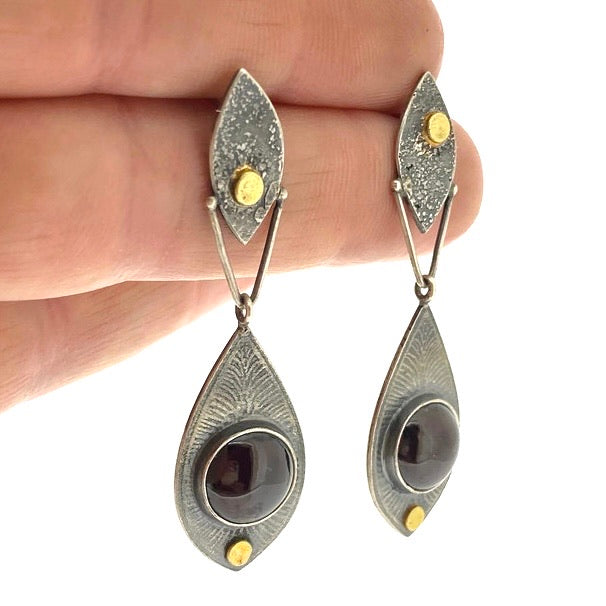 Full view of Fused Botanical Dot -Garnet Earrings being held to help give an idea of their scale.