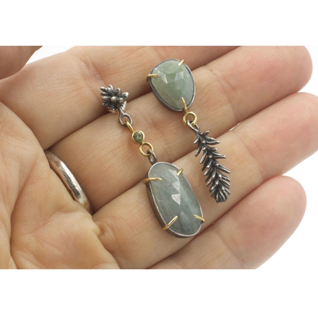 Full view of Succulent Asymmetrical Sapphire Earrings with hand in background to help give a scale of the piece.