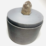 Full image of grey concrete round jar that has a quartz gemstone as the handle on the lid.