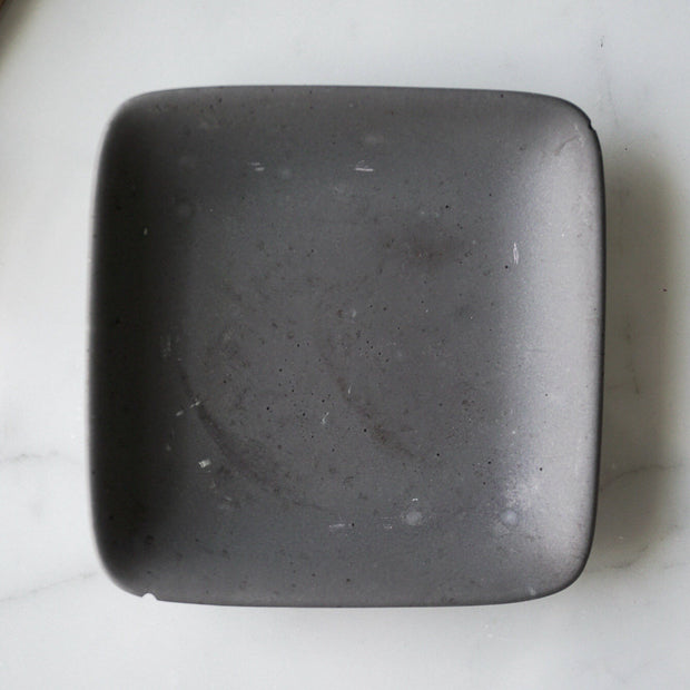 Full ariel view of square grey concrete jewelry dish.