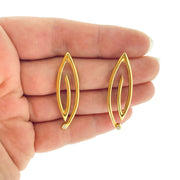 Full image if Golden Marquise Spiral Earrings with hand in background to give idea of scale. These earrings are made of gold and have a set diamond at their ends. 