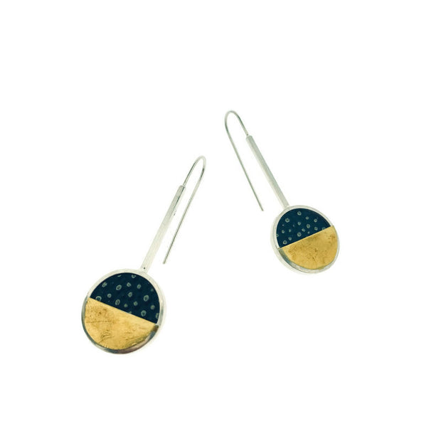 W.N. Earrings on a white background. These dangle earrings are of a circle that the bottom half is if gokd and top black learher with textured dots. 