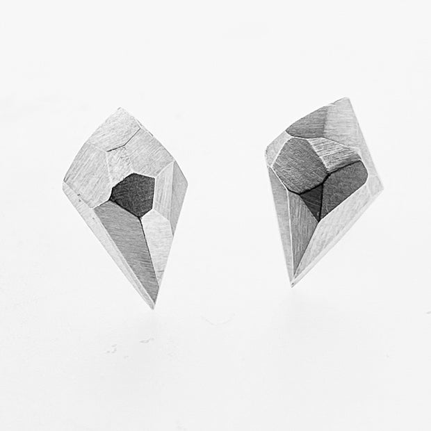 Full view of faceted stud earrings in the shape of a diamond with a faceted texture on top of them.