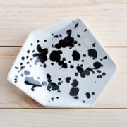 Full image of porcelain geometric ring dish with what looks like black ink spots on top of a white finish.