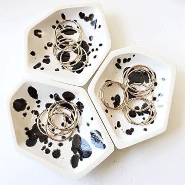 Full image of all three geometric ring dishes placed together with rings inside each dish to give a sense of size of dish. These dishes have what look like black ink spots on top of a white finish.