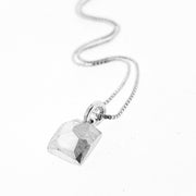 Angled view of square pendant on silver chain.