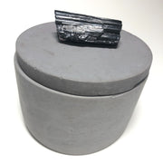 Full image of grey concrete round jar that has a black gemstone as the handle on the lid.