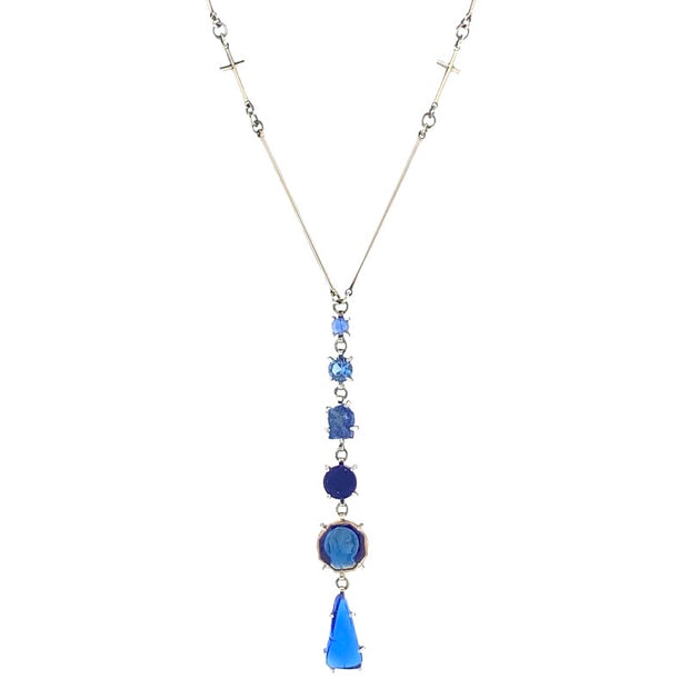 Detailed view of pendant on Long Blue Mary - Necklace. This necklace is in the shape of a Y with the use of its chain and has six set gemstones, carved blue glass, vintage french enameled Mary, lapis, rough lapis, lab aquamarine, all increasing in size and length as they go down.