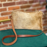 Full image of Wylie cross body bag in a blonde cowhide with brown leather strap on top of chair.