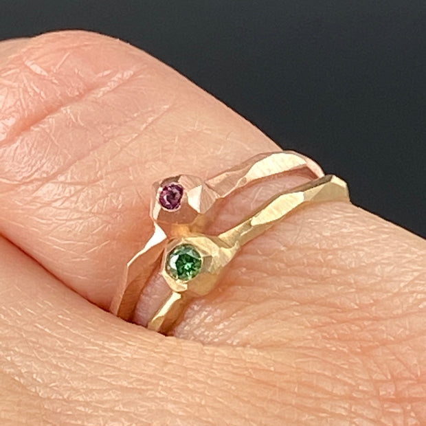Full image of green diamond and pink sapphire nugget facet rings on woman's finger to give idea of their scale.