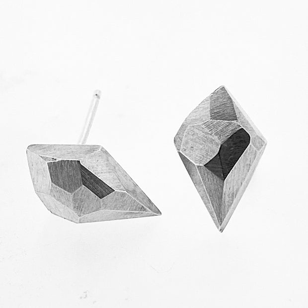 Full view of diamond faceted stud earrings with one laying down showcasing the earring post and the other propped up.