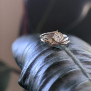 unique moissanite engagement ring and wedding band set perched atop rubber tree leaf